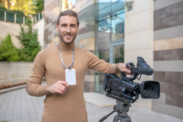 Wall Mural - Smiling operator standing near camera in front of modern building