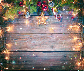 Wall Mural - rustic christmas board - fir branches and string light on wooden plank with defocused abstract snowf