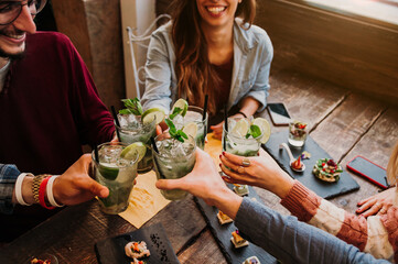 Happy friends celebrating toasting cocktails - Group of young people having fun at cocktail bar