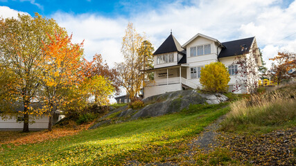 Autumn in Scandinavia. Colorful wooden houses, yards, trees. Fall season landscape. Sweden countryside in autumn. View of beautiful European garden design. Golden, yellow, brown, red colors of leaves