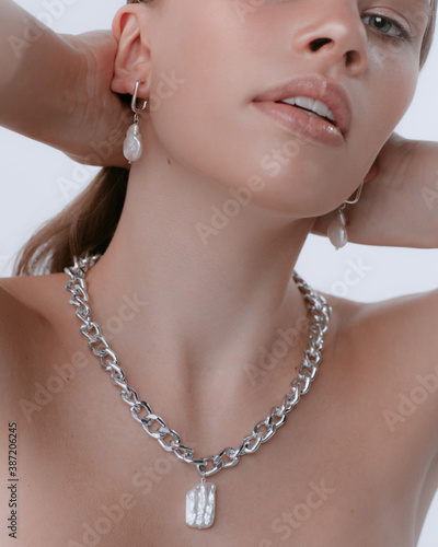 Close up portrait of young girl with natural makeup on white background in studio. Model blonde with perfect skin and in jewerly
