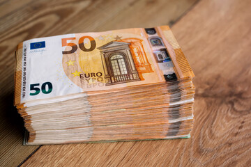 Euro money banknotes. Bundle of 50 euro bills on wooden table. Stack of euros banknotes, Money big wad packs