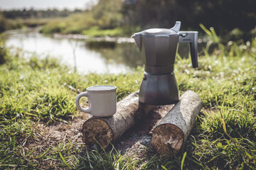 campfire coffee maker in nature near the river/picnic with a coffee maker on a campfire with cups of coffee on the background of the river
