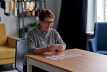 senior woman playing solitaire at home. Happy old lady plays an intellectual game