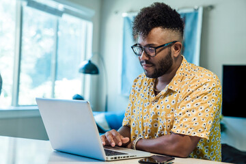 Wall Mural - man working from home on laptop computer sitting at kitchen counter