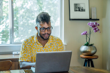 Wall Mural - man working from home on laptop computer sitting at dining room table