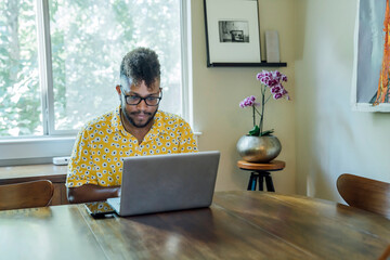 Wall Mural - man working from home on laptop computer sitting at dining room table