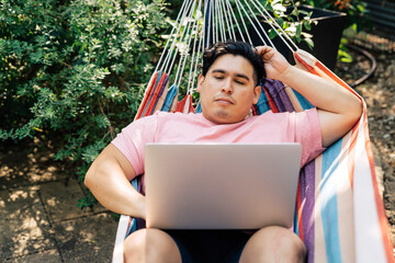 Wall Mural - man relaxing in hammock working on laptop computer