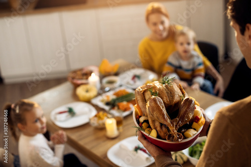 Close-up of man serving Thanksgiving turkey during family lunch in dining room.