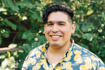 Wall Mural - Portrait of happy, smiling latinx man in bright patterned shirt standing outside in garden