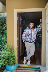 Wall Mural - Portrait of handsome, happy, smiling young man in a floral jacket standing in the doorway of his home. 