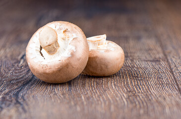 Two fresh brown mushrooms champignons on wooden table.