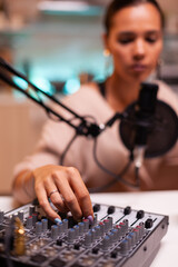 Wall Mural - Influencer in entertainment industry smiling and checking sound during broadcast from home studio in the night. Recording digital social media communication