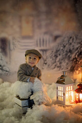 Wall Mural - Little boy, looking at flame from match, sitting in the snow