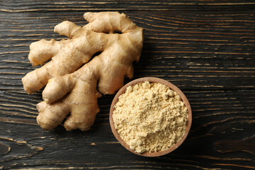 Ginger and bowl with ginger powder on wooden background