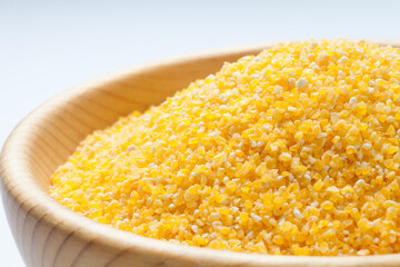 Wall Mural - Corn grits in a wooden bowl isolated on white background. Close-up.