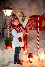 Little Child, Toddler Boy, Sending Letter To Santa In Christmas Mailbox, Christmas Decoration Around Him, Outdoor Snow Shot