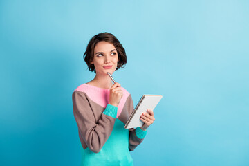 Sticker - Photo portrait of curious girl thinking about idea keeping pen notebook looking at copyspace isolated on bright color blue background