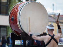 Man With Headband Playing Vertical Drum Of Japanese Musical Tradition During A Public Outdoor Event