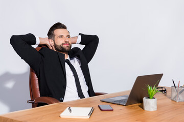 Poster - Photo of handsome cheerful business guy notebook table having break hands behind head look dreamy empty space wear black blazer shirt costume sit chair isolated grey background