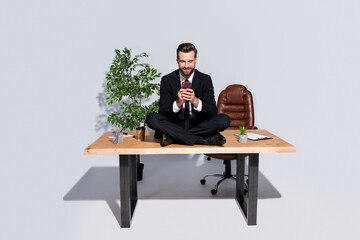 Sticker - Full length photo of handsome business guy hold telephone hands communicate colleagues sitting table legs crossed wear blazer shirt pants shoes suit isolated grey background