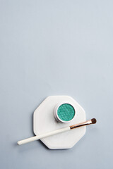 Wall Mural - Green eyeshadow and makeup brush on white stand isolated background