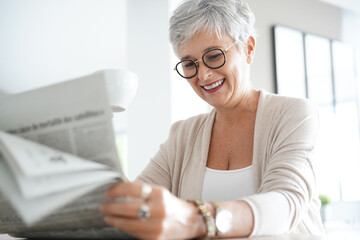 Wall Mural - Portrait of smiling mature woman at home reading newspaper