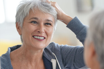 Wall Mural - Senior woman with short grey hair putting make-up on