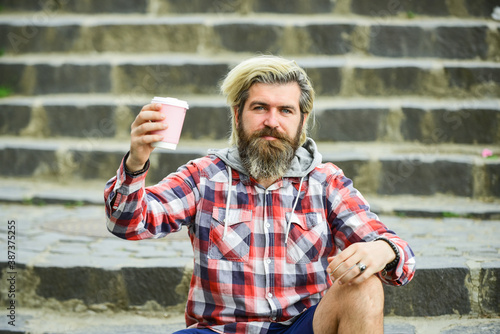 More coffee. drinking hot drink. tourist relaxing on stairs drink tea. Coffee on the go. man with a cup of coffee outdoors. Handsome calm bearded man outdoors with a cup of coffee