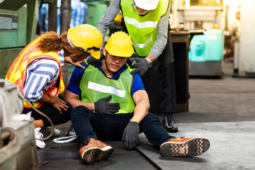 Wall Mural - First Aid. Engineering supervisor talking on walkie talkie communication while his coworker lying unconscious at industrial factory. Professional engineering teamwork concept.