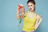 Fototapeta  - Woman with skipping rope sport exercise yellow tank top blue background