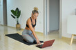 Mujer haciendo yoga en casa usando el portátil. Concepto confinamiento.