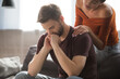 © LIGHTFIELD STUDIOS - young woman touching shoulder of tense man sitting with bowed head and holding hands near face