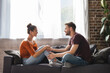 © LIGHTFIELD STUDIOS - side view of young couple talking while sitting on sofa and holding hands
