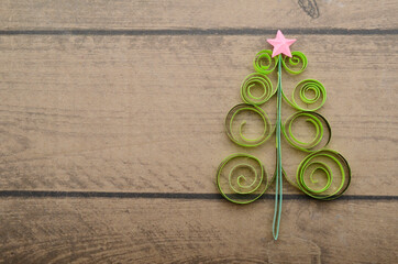 Wall Mural - A green quilling paper origami chirstmas tree with star on wooden background