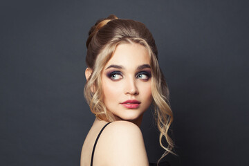 Wall Mural - stylish woman with blonde hairdo and makeup on black background