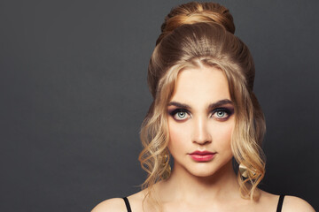 Perfect woman with blonde hairdo and makeup on black background