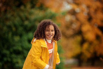 Wall Mural - Cute afro girl smiling broadly outdoors and enjoying autumn day in park.