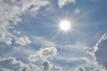 blue skies with beautiful clouds and rays from the sun shining.