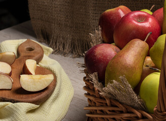 Fruit harvest .Fruit in basket and chopped on board.Apples and pears of different varieties in basket. 