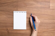 © Carolina Jaramillo - Hand holding a blue pen, ready to write, next to an open notebook, blank page