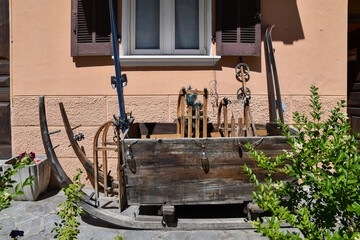 Wall Mural - Close-up of old alpine ski equipment on display in front of an house inside a large wooden sled, Aosta Valley, Italy