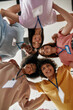 © Svitlana - Diverse young volunteers smiling, standing in circle joined and looking down at camera
