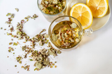 2 cup of medicinal tea from Origanum Dictamnus,  lemon and dried herb spilled on white background, closeup.