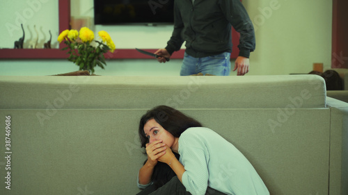Fotografía The girl hides in horror at home from a maniac with a knife.