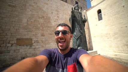 Wall Mural - happy man tourist visiting Apulia region and taking selfie in the main square of the old town of Bari 