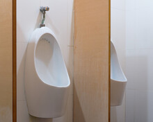 Set Of White Urinals With Wooden Dividers Inside A Male Toilet Or Restroom.