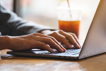 Closeup image of a woman working and typing on laptop computer in office