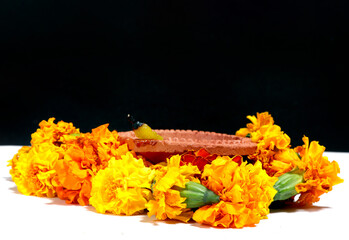 Canvas Print - Marigold flowers around Clay Oil Lamp or Diwali Diya, over white background. selective focus