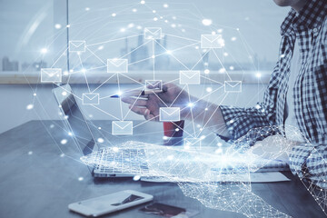 Envelop hologram drawing with businessman working on computer on background. Electronic mail concept. Double exposure.